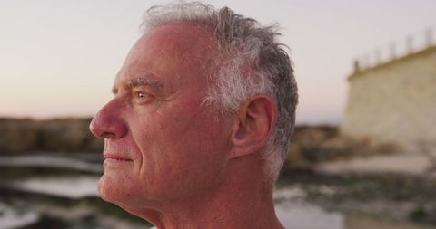 Senior Man Reflecting at Seaside During Sunset