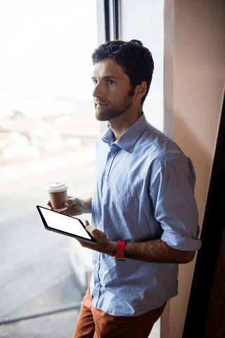 thoughtful man with tablet and coffee by large transparent window - Download Free Stock Videos Pikwizard.com