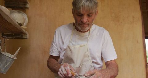 Senior man crafting pottery in rustic workshop environment