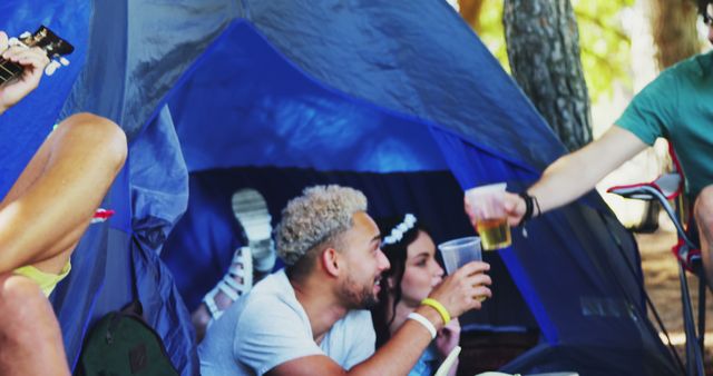 Friends lying and socializing in a blue camping tent in the forest, enjoying drinks and relaxing. Ideal for use in promotional material for outdoor gear, camping vacations, nature adventures, and social events. The image evokes feelings of leisure, friendship, and connection with nature.