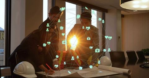 Engineering team reviewing architectural plans with digital network overlay at sunset