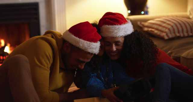 Couple Enjoying Christmas Evening by Fireplace with Santa Hats - Download Free Stock Images Pikwizard.com