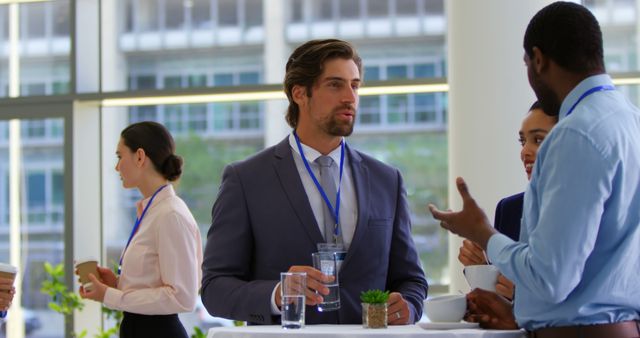 Multi ethnic business people interacting with each other while holding coffee or glass of water at table during a business seminar 4k