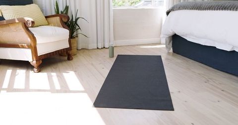 Bright bedroom with yoga mat and cozy wooden chair