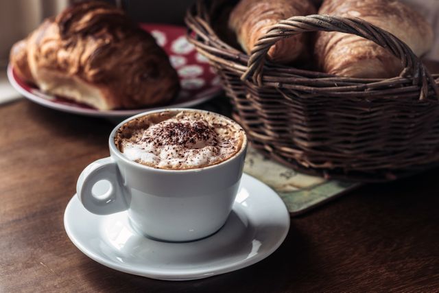 Freshly brewed cappuccino with croissants on wooden table in cozy café - Download Free Stock Photos Pikwizard.com