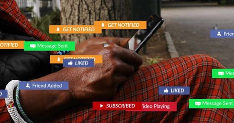 Senior man scrolling smartphone receiving social media notifications while sitting by tree