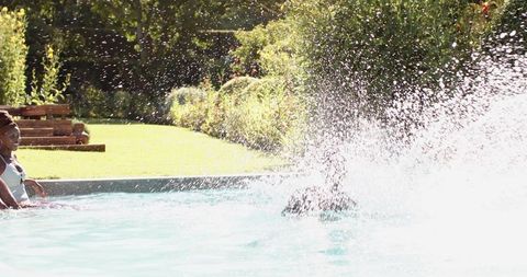 Siblings splashing fun in sunlit pool