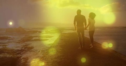 Couple Walking Hand-in-Hand on Jetty at Golden Sunset with Lens Flare and Silhouettes
