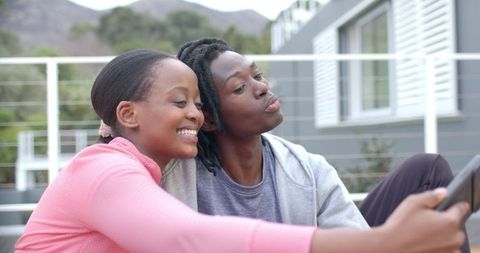 African american couple smiling and taking selfie on residential deck with mountain view