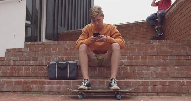 Teen boy sitting on skateboard texting on phone - Download Free Stock Images Pikwizard.com