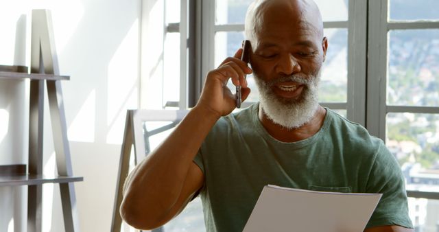 Man with Gray Hair Reviewing Documents and Talking on Phone at Home - Download Free Stock Images Pikwizard.com