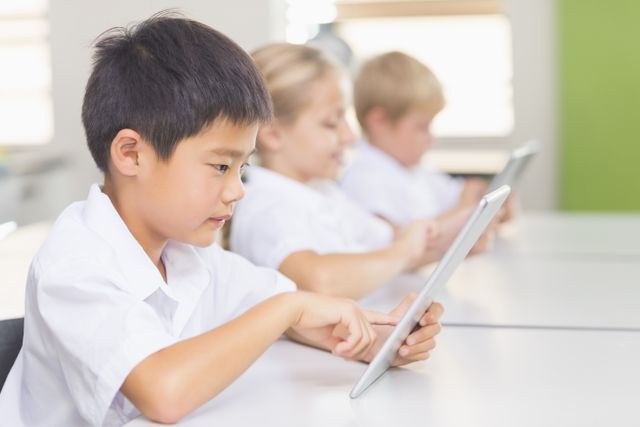 Children in a classroom using tablets for learning. Ideal for educational content, technology in education, modern classrooms, and interactive learning materials.