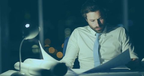 Business professional review plans in night office environment