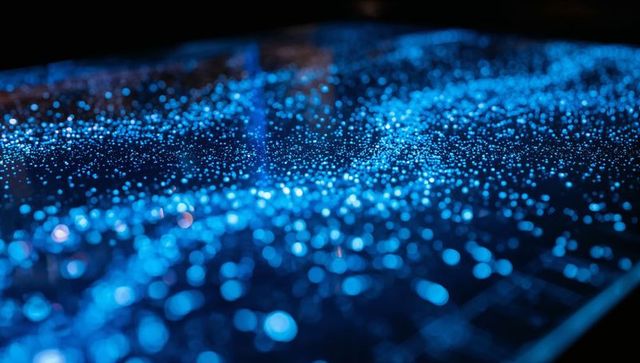 Futuristic blue bokeh matrix glowing on reflective glass panel, macro sparkle field depth