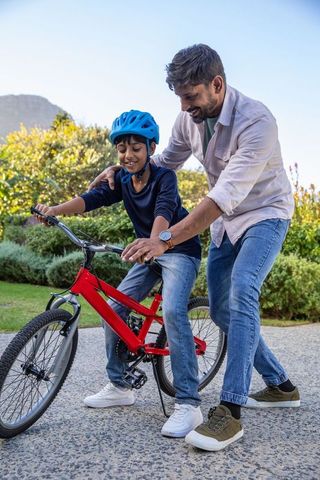 Father Teaching Son to Ride Bike Outdoors on Sunny Day