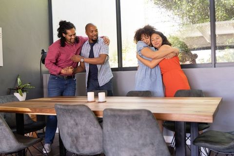 Friends Embracing in Modern Dining Room Celebrating Togetherness