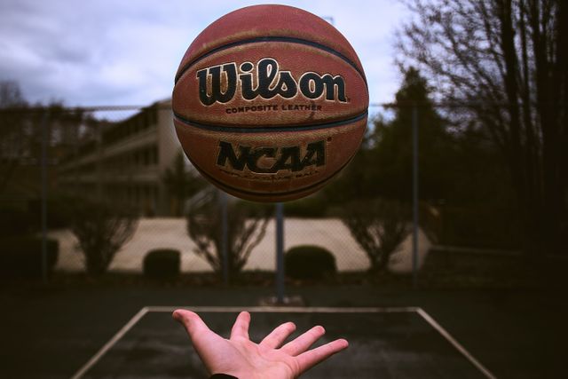 View of a hand throwing a basketball in the air against basketball court. Sports and competition concept