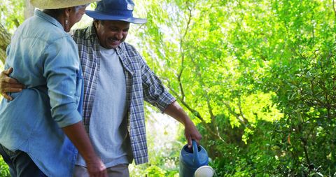Middle-Aged Men Enjoying Gardening Together with Watering Can