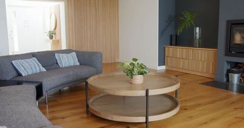 Round two-tier oak coffee table featuring potted plant and gray sectional living room
