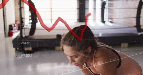 Bending athlete holding knees recovering after intense cardio with red performance graph