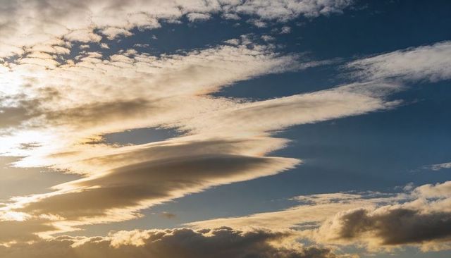 Lenticular Cloud Glowing Over Sunset Horizon with Iridescent Bands and Layered Cirrus