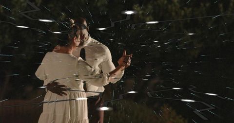 Mature couple dancing at night in garden with glowing light trails and intimate embrace