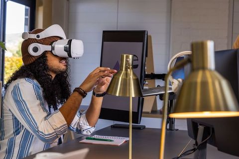Young professional wearing vr headset at modern workspace manipulating virtual interface