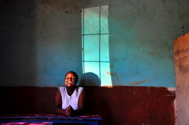 Happy African Woman Laughing in Sunlit Room - Download Free Stock Photos Pikwizard.com