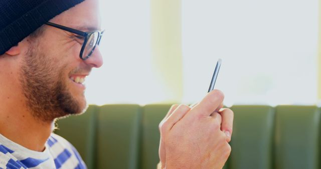 Smiling man using smartphone in cozy cafe - Download Free Stock Images Pikwizard.com