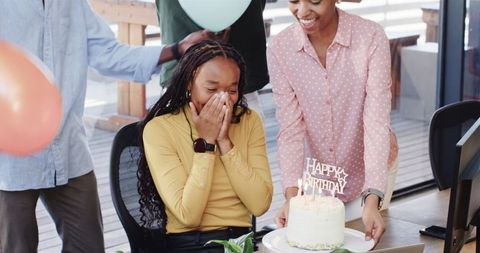Office birthday celebration with surprise cake and joyful colleagues