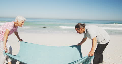 Senior Couple Relaxing on Sunny Beach with Blanket