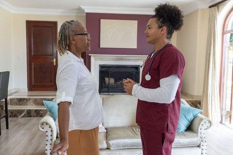 Young male nurse consulting senior african american woman during in-home care visit