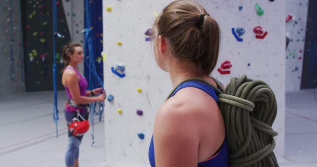 Portrait of caucasian woman with rope on her back turning to camera at indoor climbing wall. fitness and leisure time.