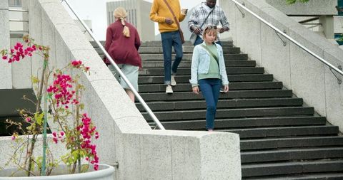 Urban commuters walking down granite staircase with bougainvillea planter and coffee cup