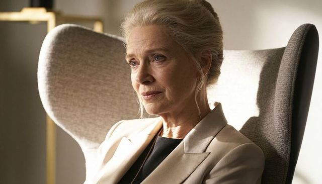 Contemplative senior woman wearing beige blazer in wingback chair, executive calm portrait