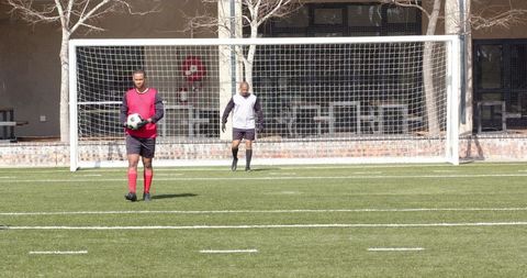 Soccer Player Kicking Ball Towards Goal on a Sunny Day
