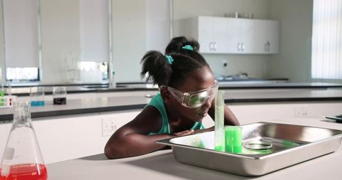 African american girl conducting classroom science experiment wearing goggles
