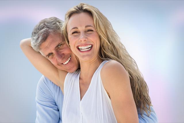 Portrait capturing joyful senior couple embracing and smiling outdoors against clear blue sky. Ideal for use in retirement planning brochures, health and wellness advertisements, relationship and family-themed promotions, and lifestyle blogs.