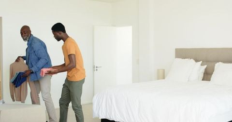 Father and Son Organizing Clothes in Modern Bedroom