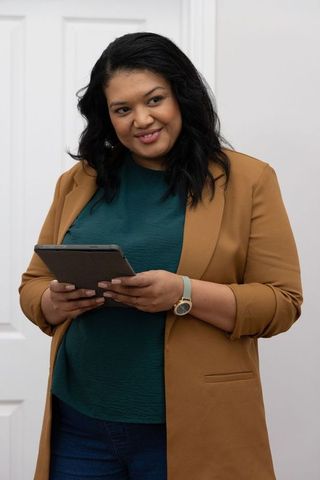 African american professional woman holding tablet wearing camel blazer and teal blouse