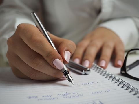 Close-up of hand writing in notebook with fountain pen