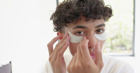 Man Applying Skincare Patches Under Eyes for Self-Care
