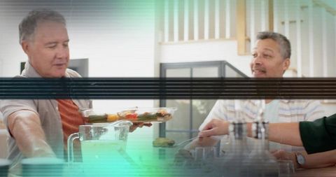 Adults sharing and passing platter around kitchen table during casual home gathering, candid meal