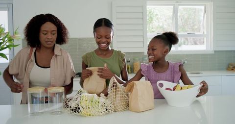 Unpacking groceries and arranging produce at bright modern kitchen island with reusable bags