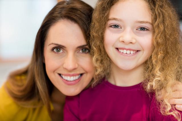 Portrait of mother and daughter smiling at home
