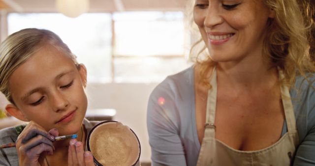 Woman and Girl Smiling While Painting Pottery Together Indoors - Download Free Stock Images Pikwizard.com