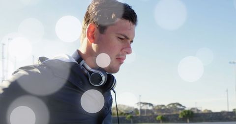 Young Adult with Headphones Lit by Soft Light Flare Outdoors