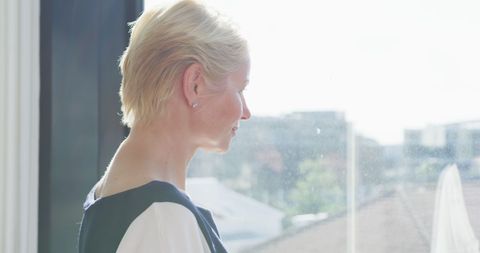 Thoughtful Businesswoman Looking Out Office Window with Natural Light