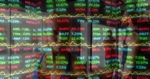 Traders reflecting in multi-colored stock ticker panels with yellow trend lines in office