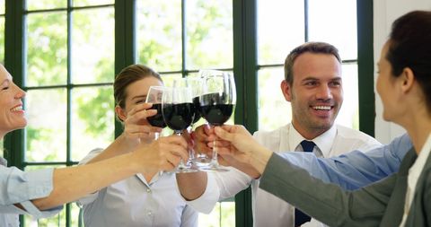 Team Celebrating Success in Restaurant with Red Wine Toast